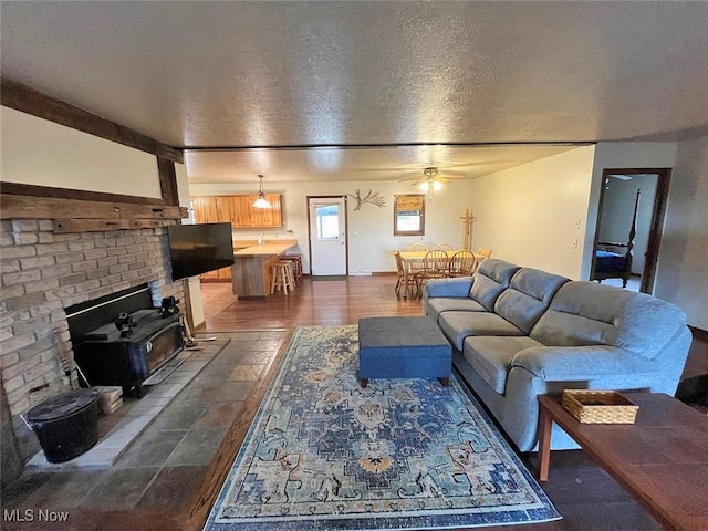 living area featuring a ceiling fan, a textured ceiling, and a wood stove