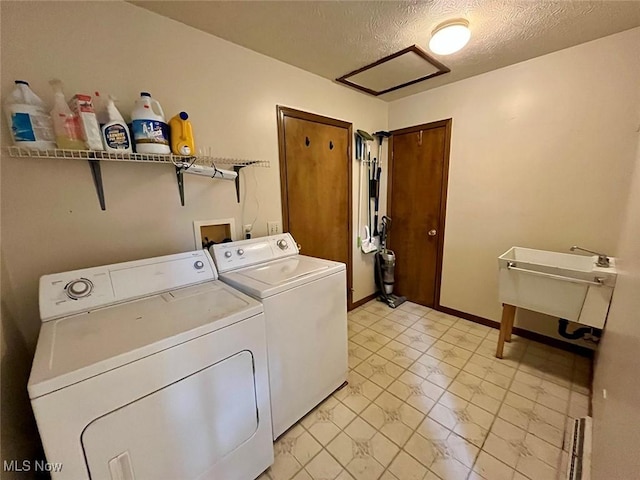 washroom with washing machine and clothes dryer, attic access, laundry area, a textured ceiling, and a sink