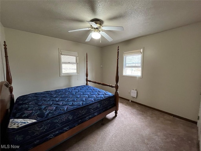 bedroom with light colored carpet, baseboards, a textured ceiling, and ceiling fan