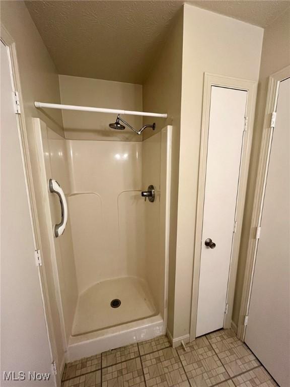 bathroom featuring a shower stall and a textured ceiling