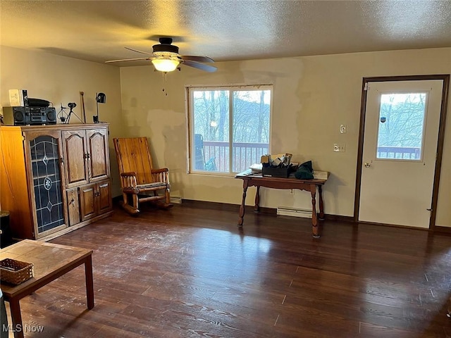 living area with dark wood finished floors, a ceiling fan, baseboards, and a textured ceiling