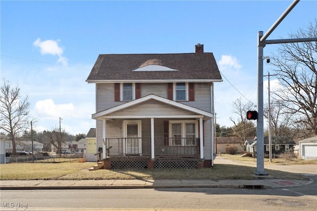 view of front of house featuring a front yard, roof with shingles, covered porch, and a chimney