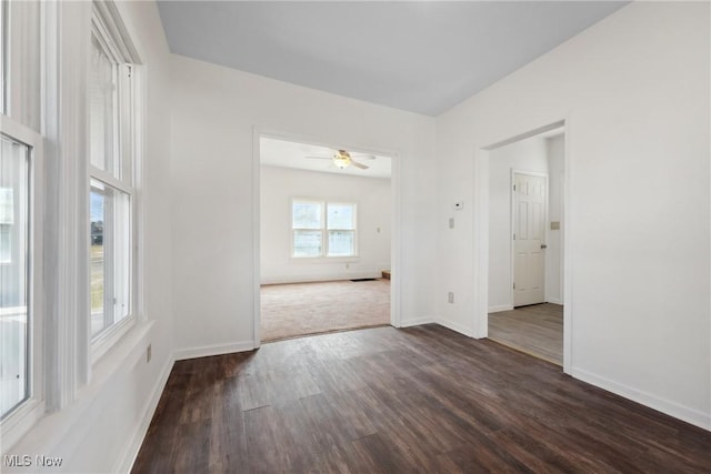 spare room with a ceiling fan, dark wood-style floors, and baseboards