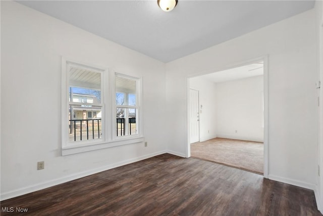 spare room featuring baseboards and dark wood-style flooring