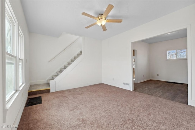 unfurnished living room featuring visible vents, carpet floors, and stairway