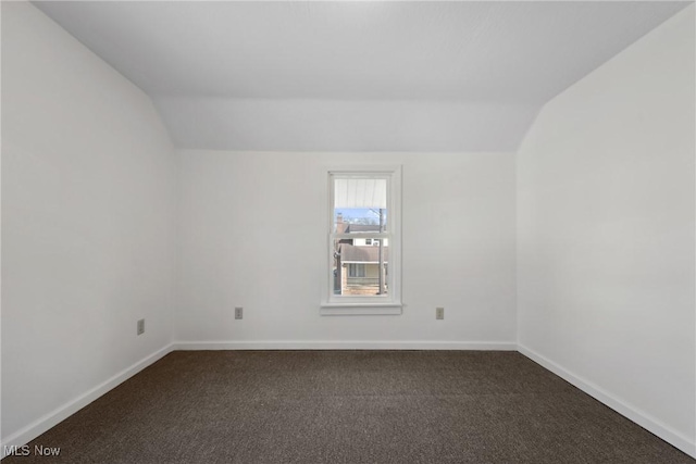 unfurnished room with lofted ceiling, baseboards, and dark colored carpet