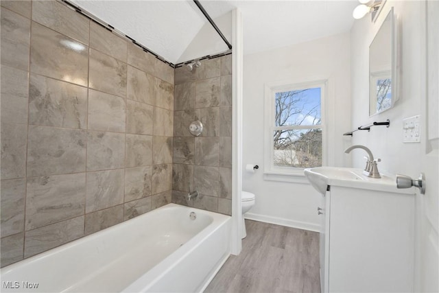 bathroom with toilet, wood finished floors, washtub / shower combination, baseboards, and vanity