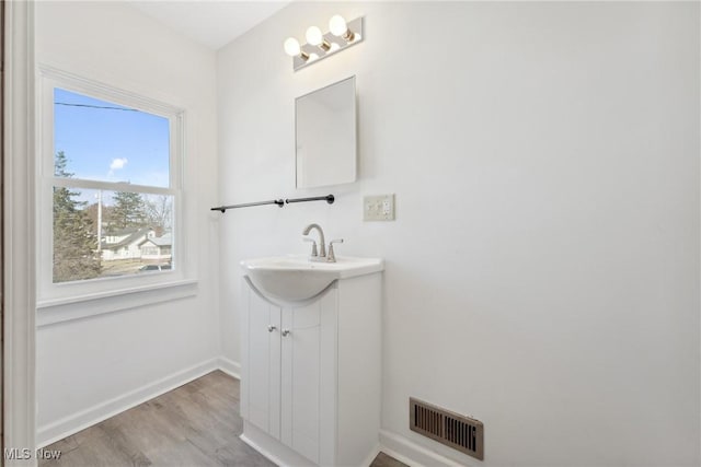 bathroom with visible vents, vanity, baseboards, and wood finished floors