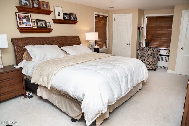 bedroom featuring light colored carpet and radiator