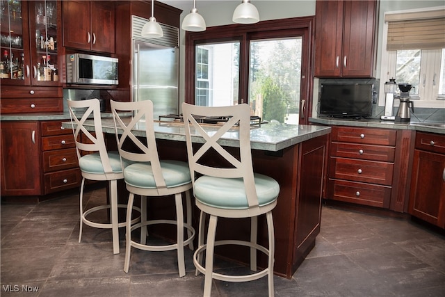 kitchen featuring a center island, glass insert cabinets, pendant lighting, a breakfast bar, and stainless steel appliances