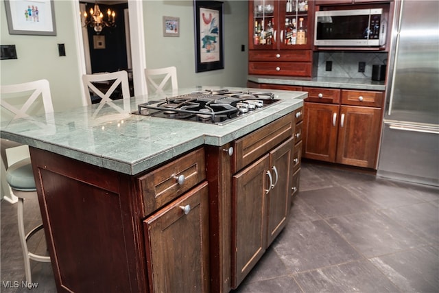 kitchen featuring a breakfast bar area, light countertops, appliances with stainless steel finishes, tasteful backsplash, and a center island