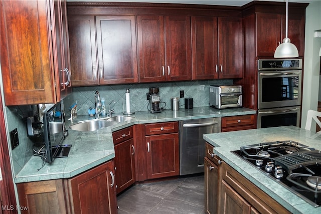 kitchen with tasteful backsplash, decorative light fixtures, light countertops, stainless steel appliances, and a sink