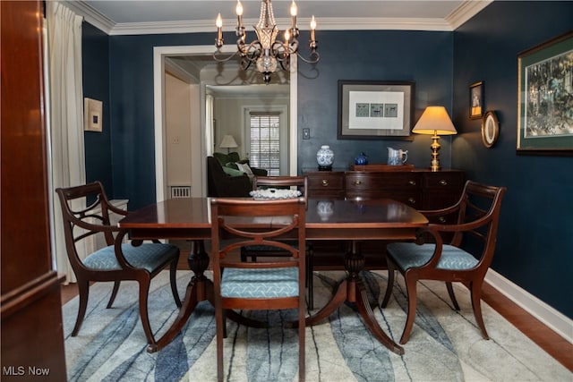 dining room with a chandelier, crown molding, baseboards, and wood finished floors