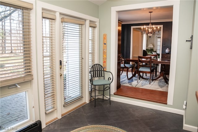 doorway with a notable chandelier, baseboards, and ornamental molding