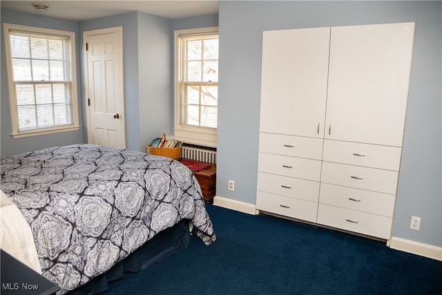 bedroom with baseboards, dark carpet, and radiator heating unit