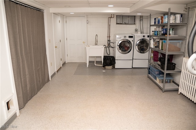 washroom featuring laundry area, washing machine and dryer, light floors, and a sink