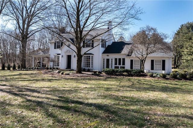 colonial inspired home featuring a gazebo, a front lawn, and a chimney