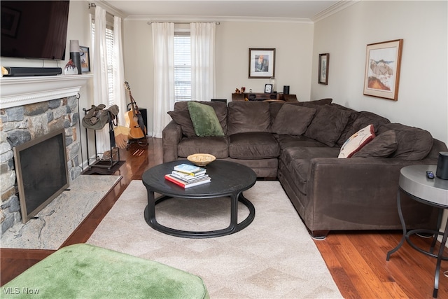 living area featuring a stone fireplace, crown molding, and wood finished floors