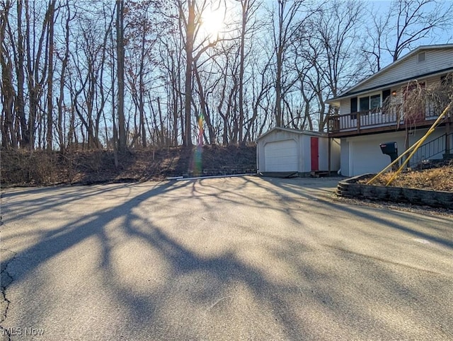 view of yard with aphalt driveway, a detached garage, and an outbuilding