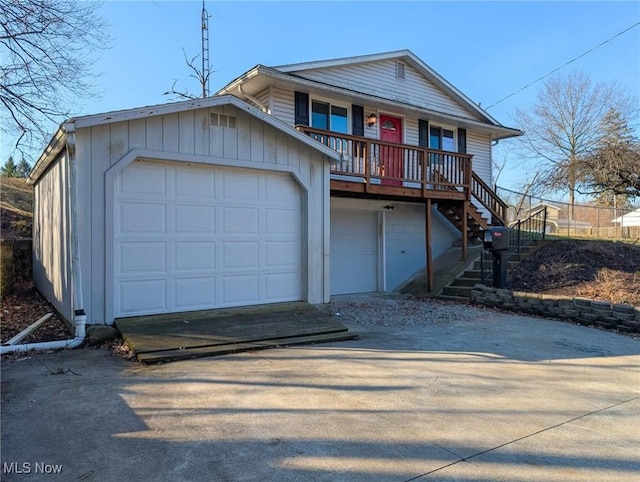 view of front of house featuring a garage, a porch, concrete driveway, and stairs