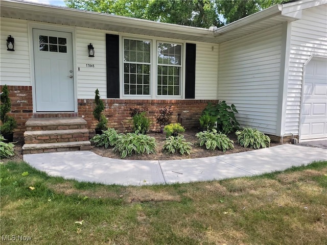 property entrance with brick siding and a garage