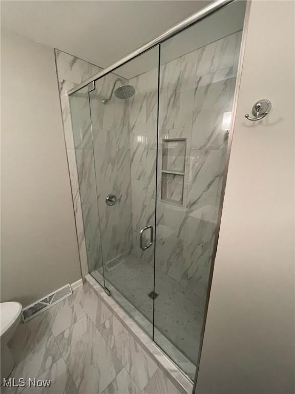 full bath featuring visible vents, a marble finish shower, baseboards, toilet, and marble finish floor