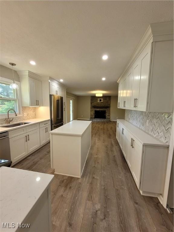 kitchen with a center island, open floor plan, freestanding refrigerator, white cabinets, and a sink