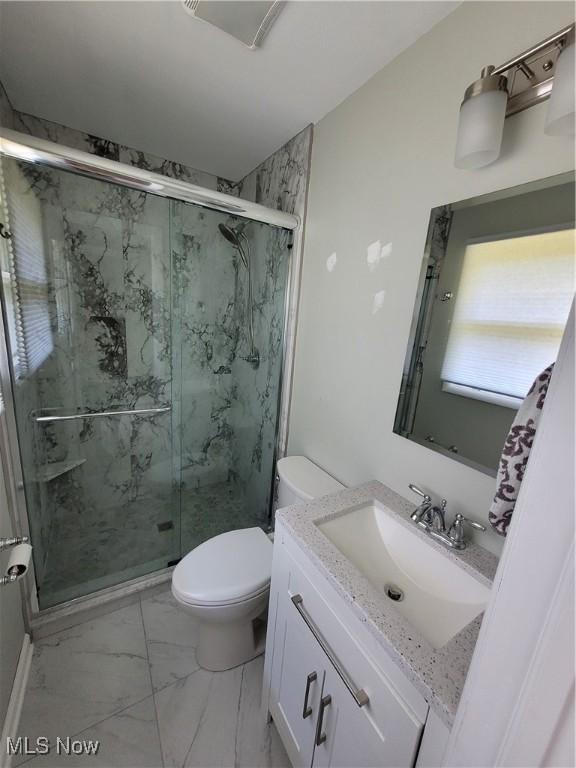 bathroom featuring a marble finish shower, marble finish floor, toilet, and vanity