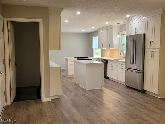 kitchen with a sink, a kitchen island, wood finished floors, light countertops, and high end refrigerator