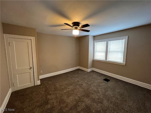 unfurnished room with dark colored carpet, baseboards, and ceiling fan