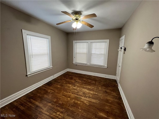 spare room with baseboards, wood finished floors, and a ceiling fan