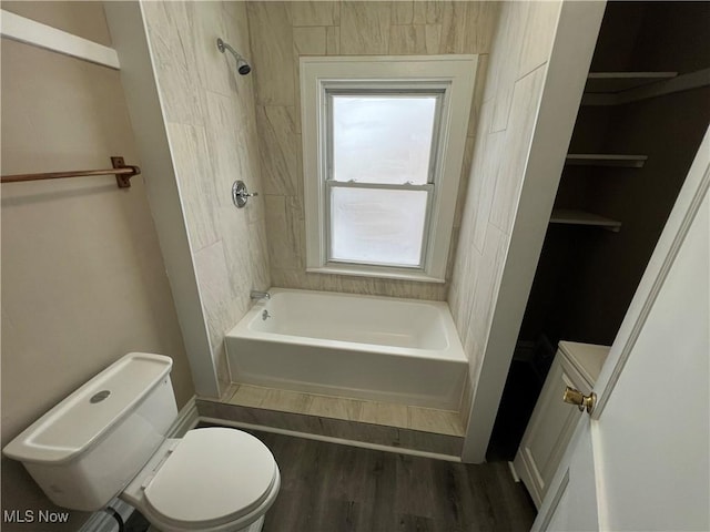 bathroom with bathing tub / shower combination, toilet, and wood finished floors