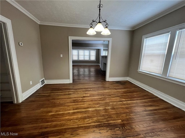 unfurnished dining area with baseboards, visible vents, dark wood finished floors, ornamental molding, and a notable chandelier