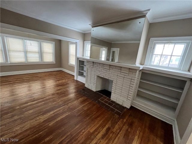 unfurnished living room featuring dark wood finished floors, a brick fireplace, a wealth of natural light, and ornamental molding