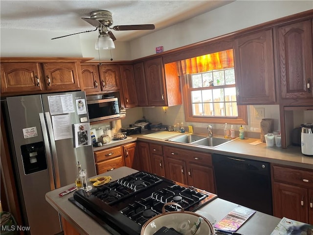 kitchen featuring brown cabinets, a ceiling fan, a sink, stainless steel appliances, and light countertops