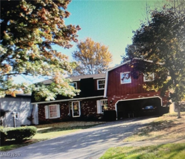 view of front of home featuring a gambrel roof, an attached garage, and gravel driveway