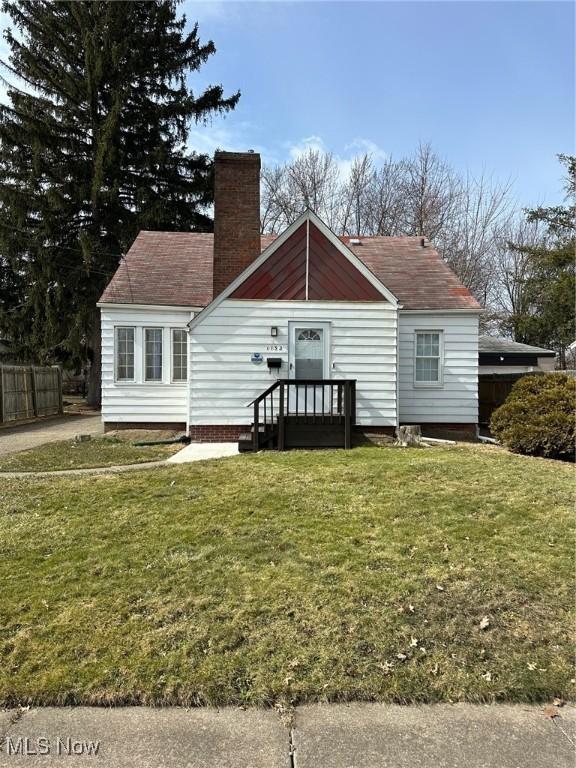 view of front facade featuring a chimney, a front yard, and fence