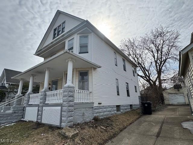 view of front of property featuring an outbuilding, a porch, concrete driveway, and a detached garage