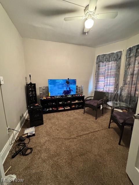 living area with a ceiling fan, baseboards, and carpet floors