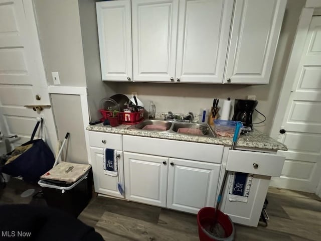 interior space with white cabinets, dark wood-style floors, and a sink