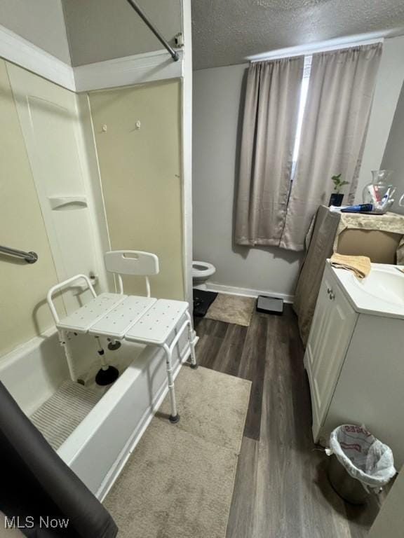 full bathroom featuring vanity, wood finished floors, bathtub / shower combination, a textured ceiling, and toilet