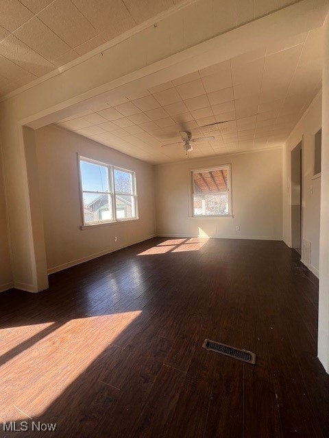 spare room featuring ceiling fan, wood finished floors, visible vents, and baseboards