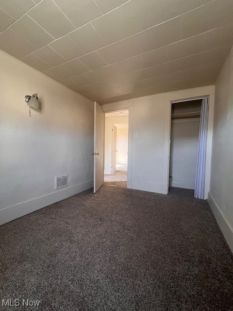 unfurnished bedroom featuring a closet, visible vents, baseboards, and carpet floors