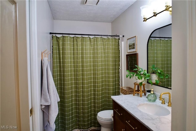 full bathroom featuring a textured ceiling, vanity, and toilet