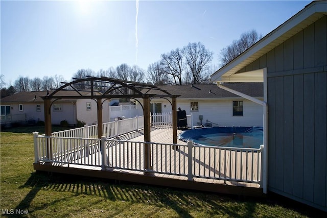 rear view of house featuring a gazebo, a wooden deck, a lawn, and a fenced in pool