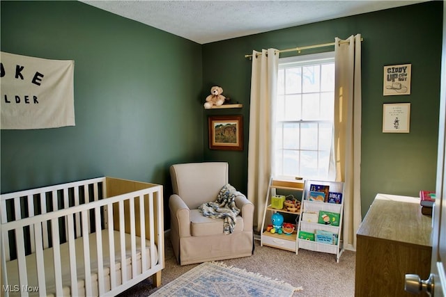 bedroom featuring a crib, a textured ceiling, and carpet