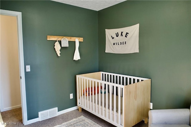 carpeted bedroom featuring visible vents, a crib, and baseboards