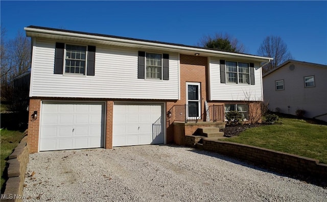 raised ranch featuring a front yard, brick siding, an attached garage, and driveway