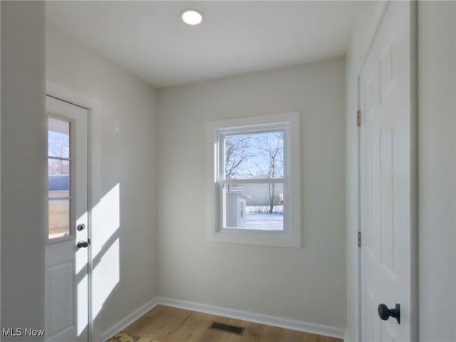 foyer entrance featuring visible vents, plenty of natural light, baseboards, and light wood finished floors