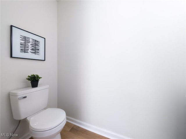 bathroom featuring toilet, wood finished floors, and baseboards